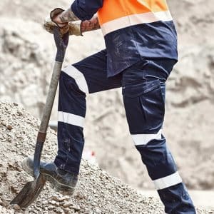 Mens Essential Stretch Taped Cargo Pant in navy blue with reflective stripes, worn by a person shovelling gravel.